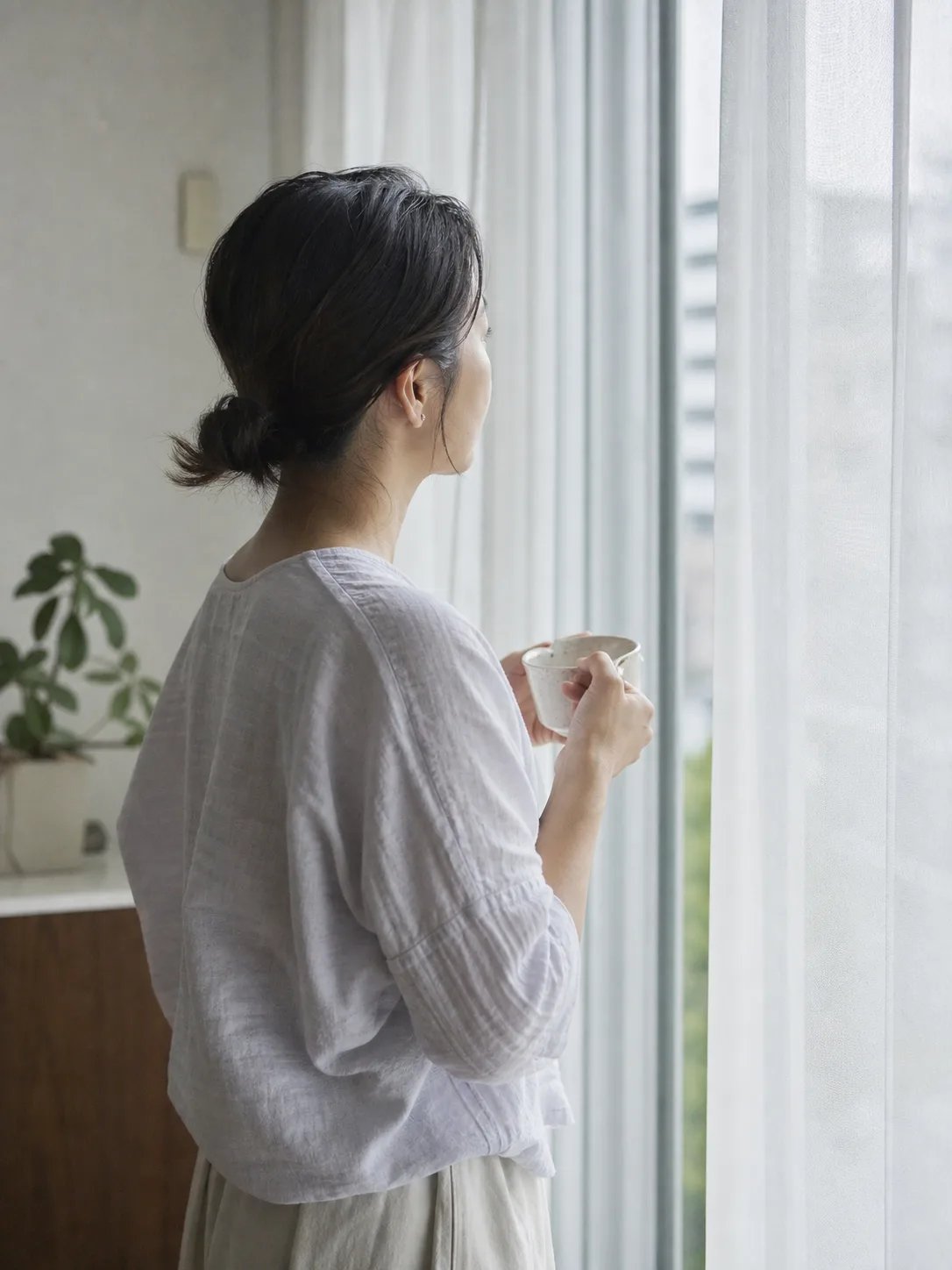窓辺で静かに外を見る母親